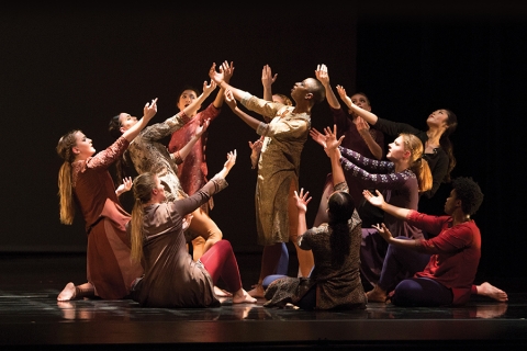 Dancers on stage, lifting arms into the air