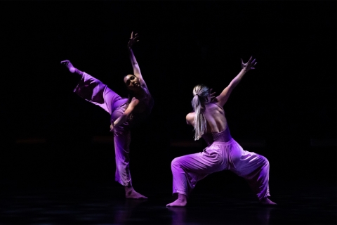 Dancers on stage with legs and arms extended into air